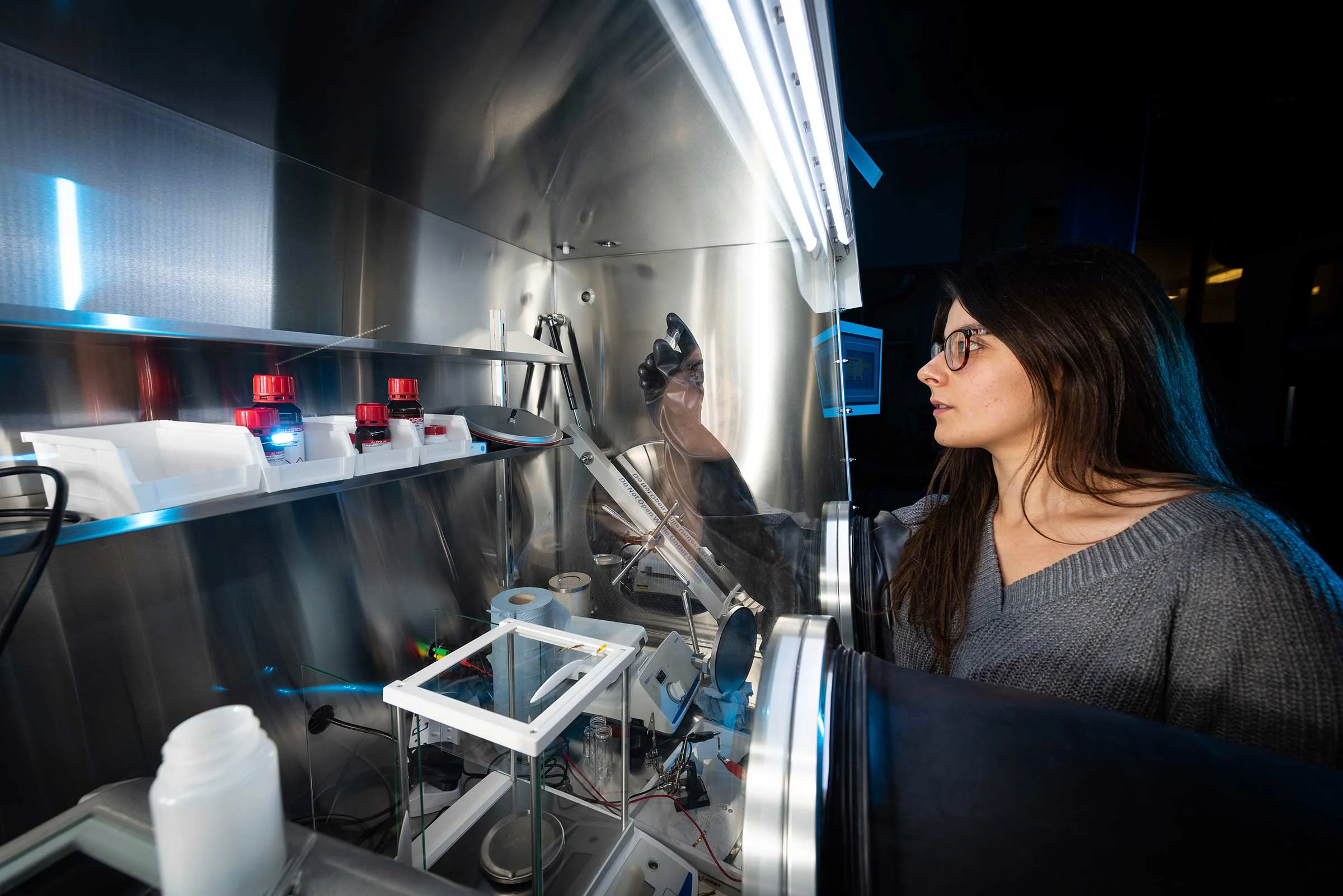 Women in front of screen with her hand in a glove working with things behind the screen
